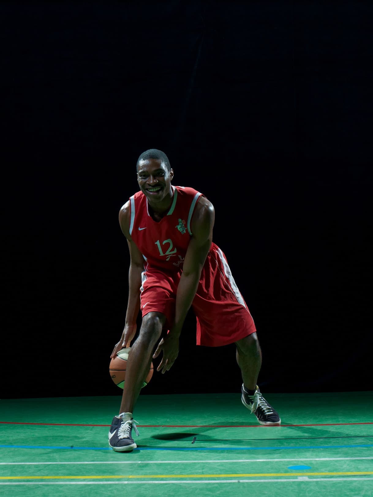 Uche Umekwe in a red number 12 jersey, dribbling a basketball.