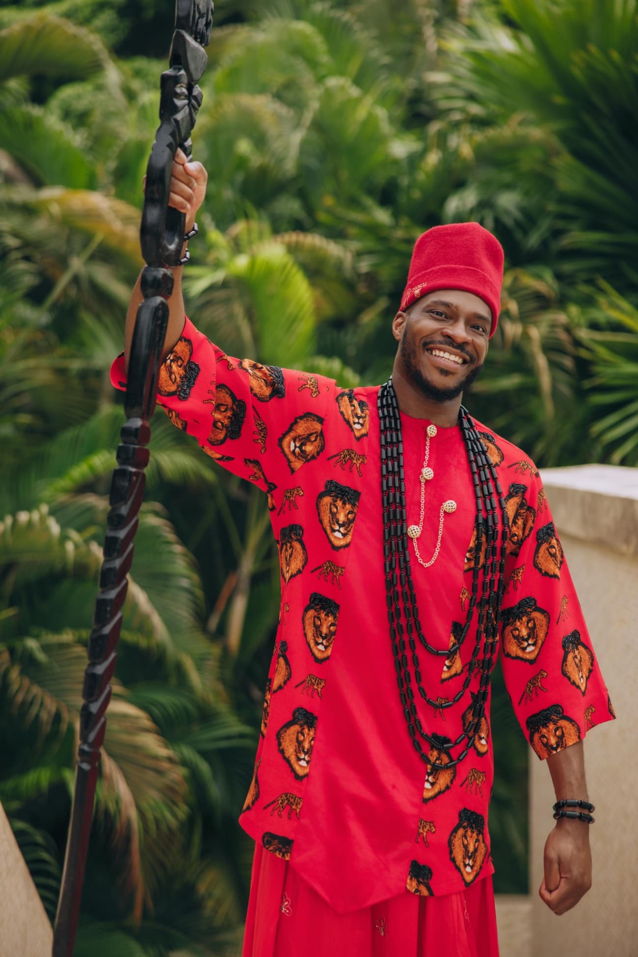Uche Umekwe in traditional Igbo dress, holding a carved staff.